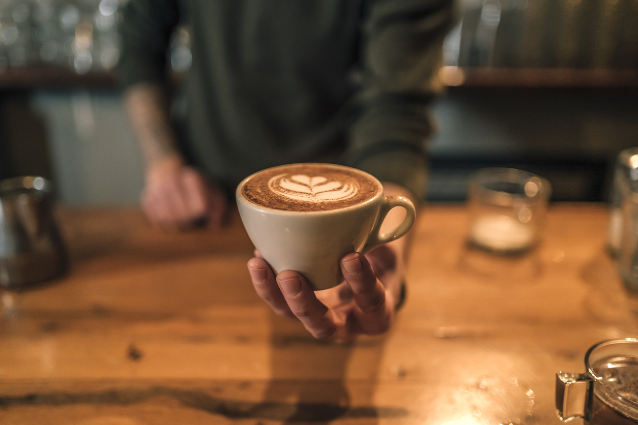 Someone serving a cup of espresso from a local coffee shop